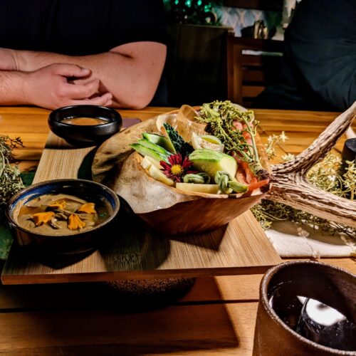 A wooden platter full of brightly colored vegetables at a fine dining establishment.